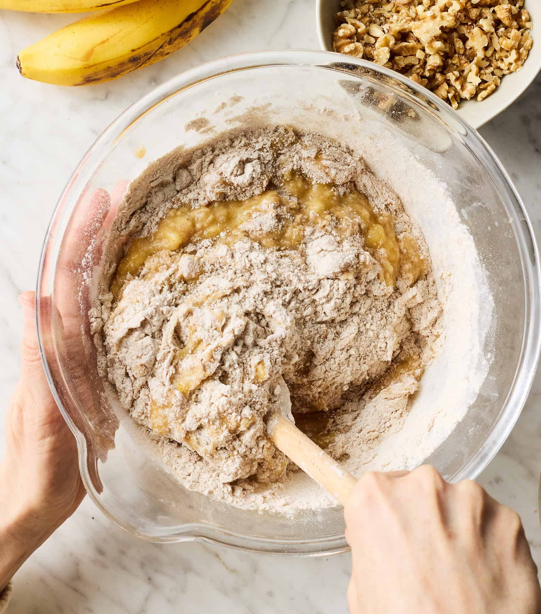 Mixing dry and wet ingredients together in glass mixing bowl
