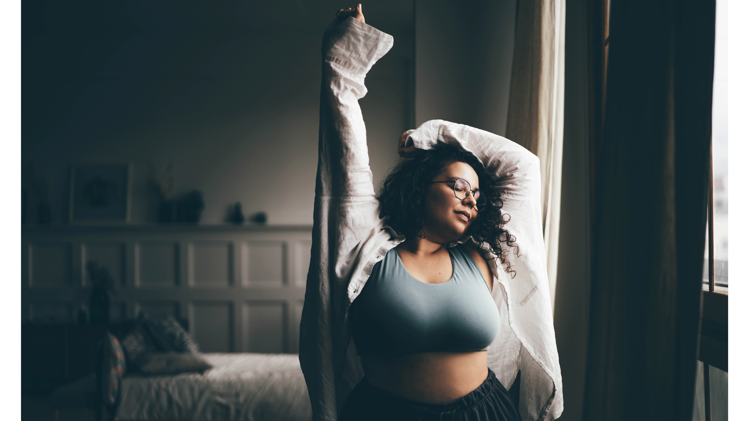 Woman in a sports bra stretching and looking comfortable in herself before she practices yoga