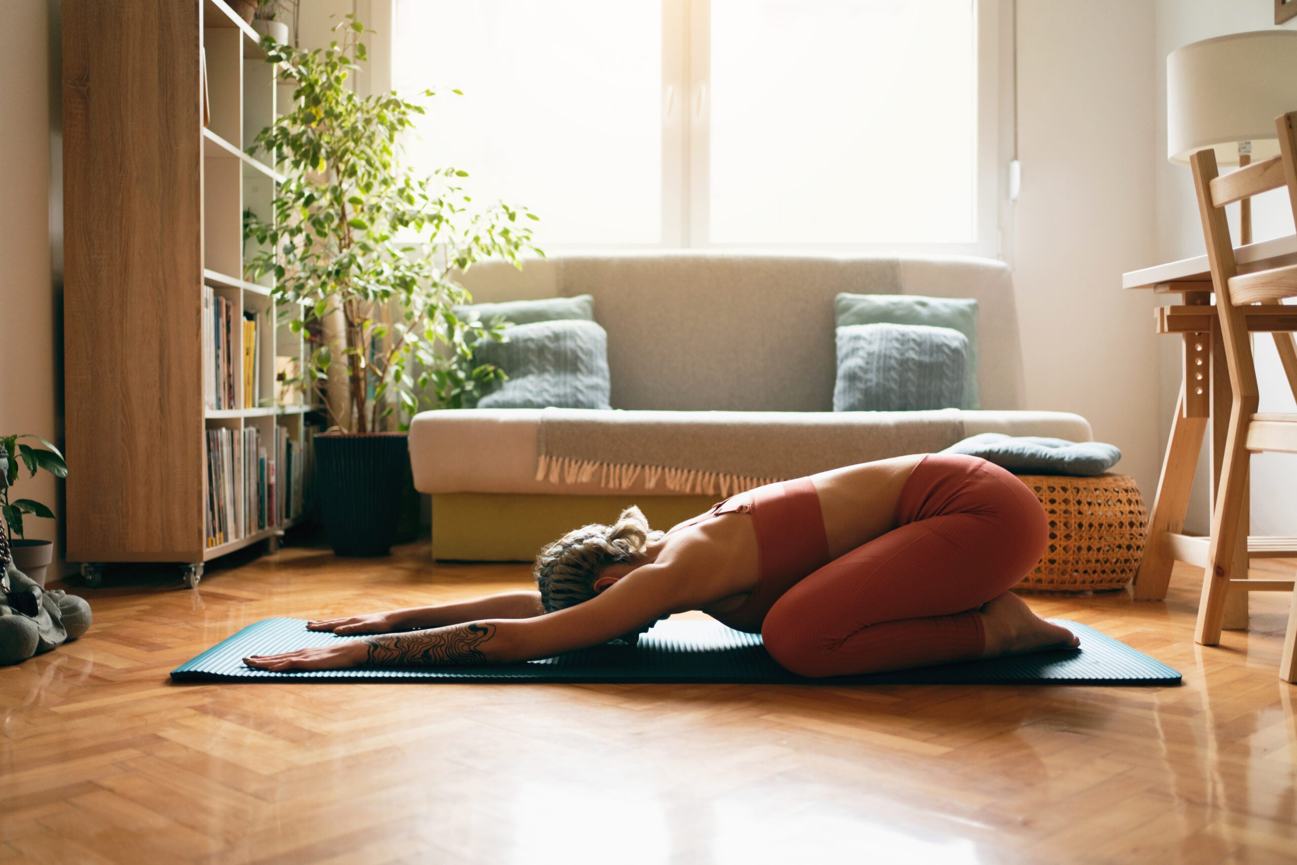 Side angle of a young woman doing child's pose in yoga.