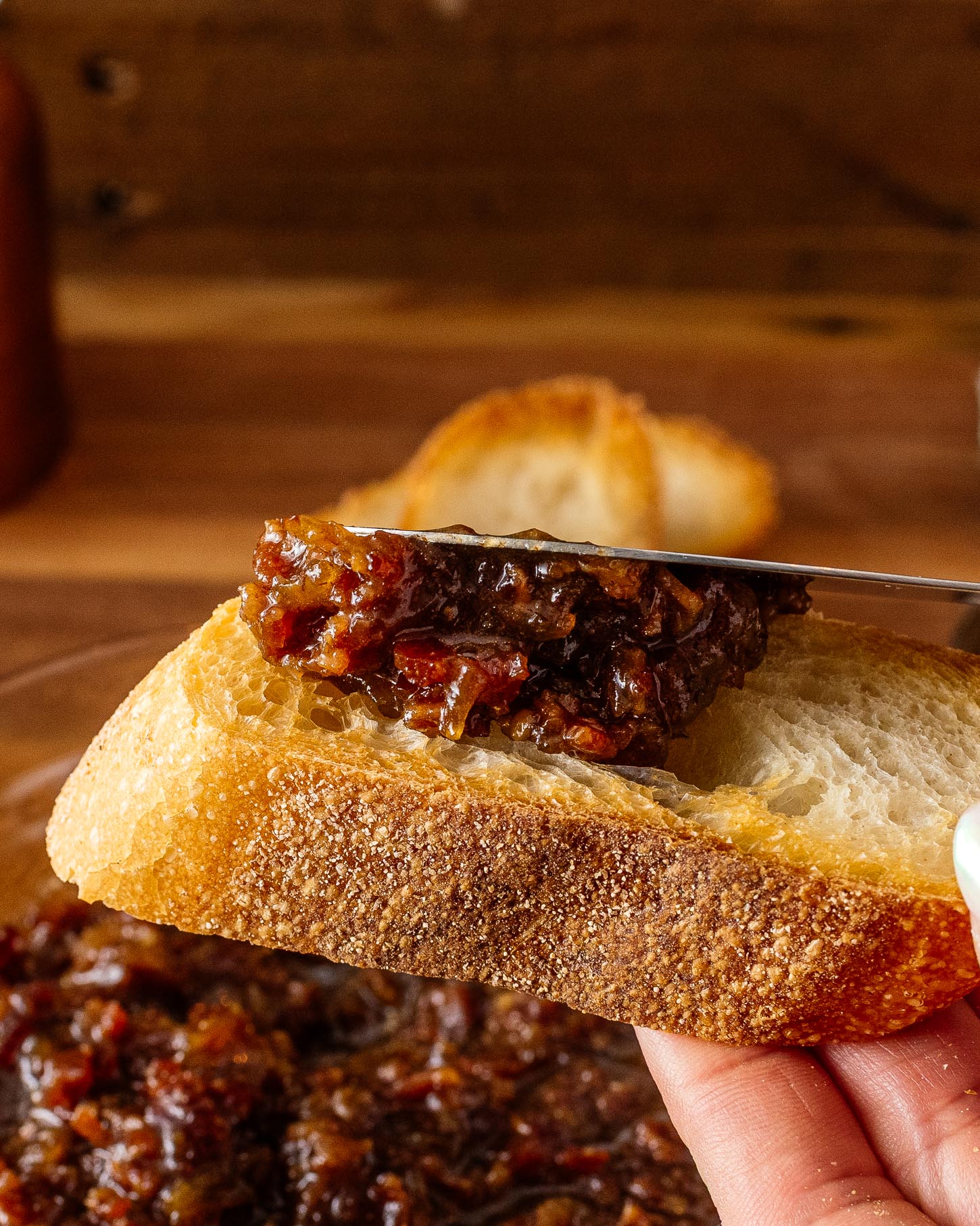 spreading bacon jam on baguette